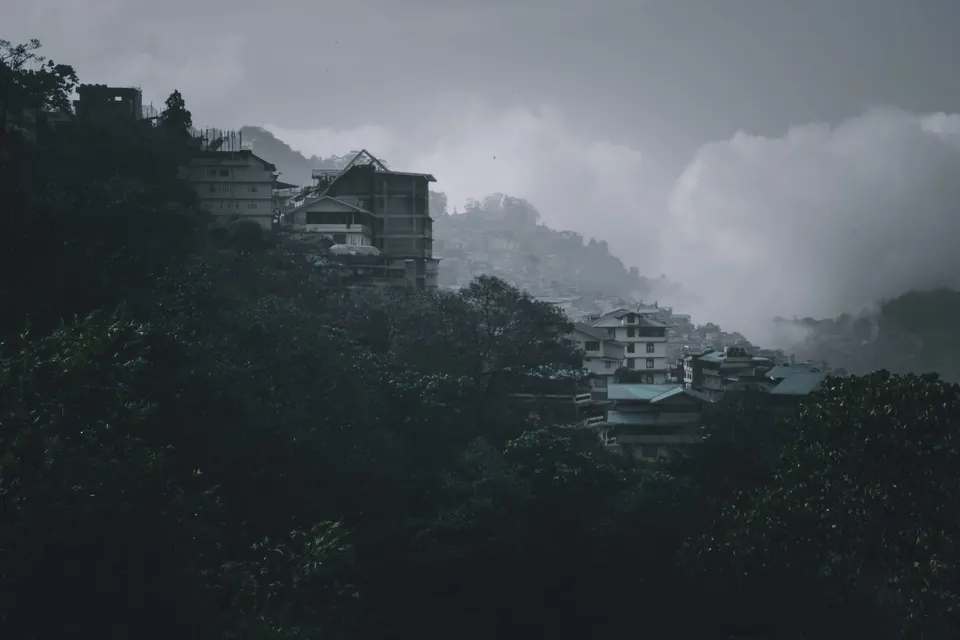 Misty view of a hillside village in Sikkim, India, enveloped in clouds.
