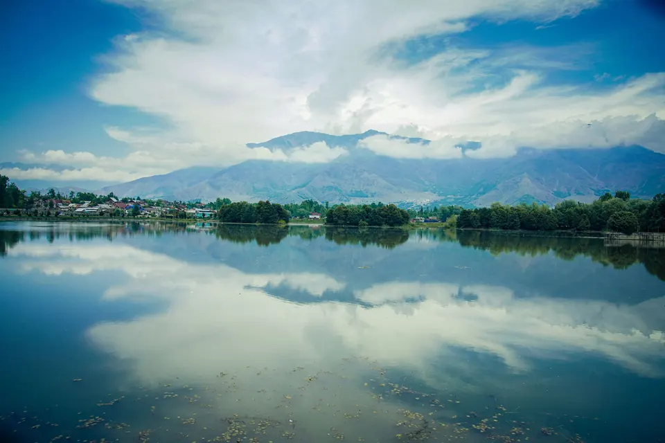 Peaceful landscape of Dal Lake with mountains and clear reflections in Srinagar, India.