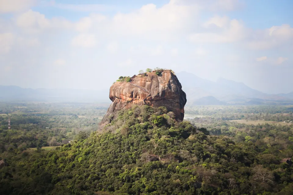 View of the iconic Sigiriya Rock Fortress, surrounded by lush vegetation in Sri Lanka.