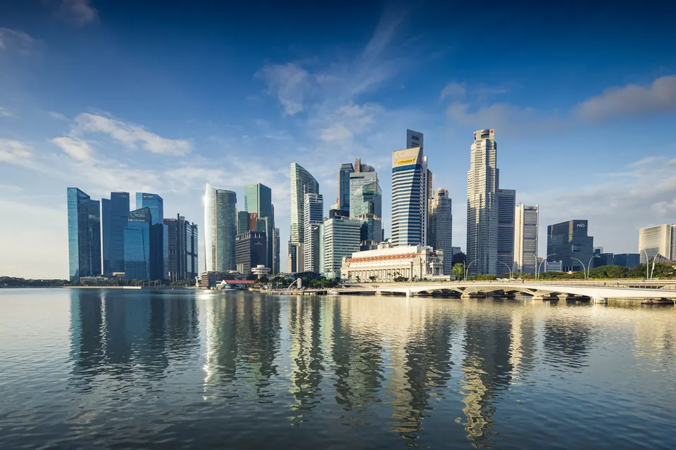 Capture of Singapore's modern skyline featuring reflective skyscrapers against a blue sky.