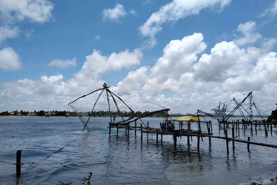 Traditional Chinese fishing nets silhouetted against a clear blue sky in Kerala.