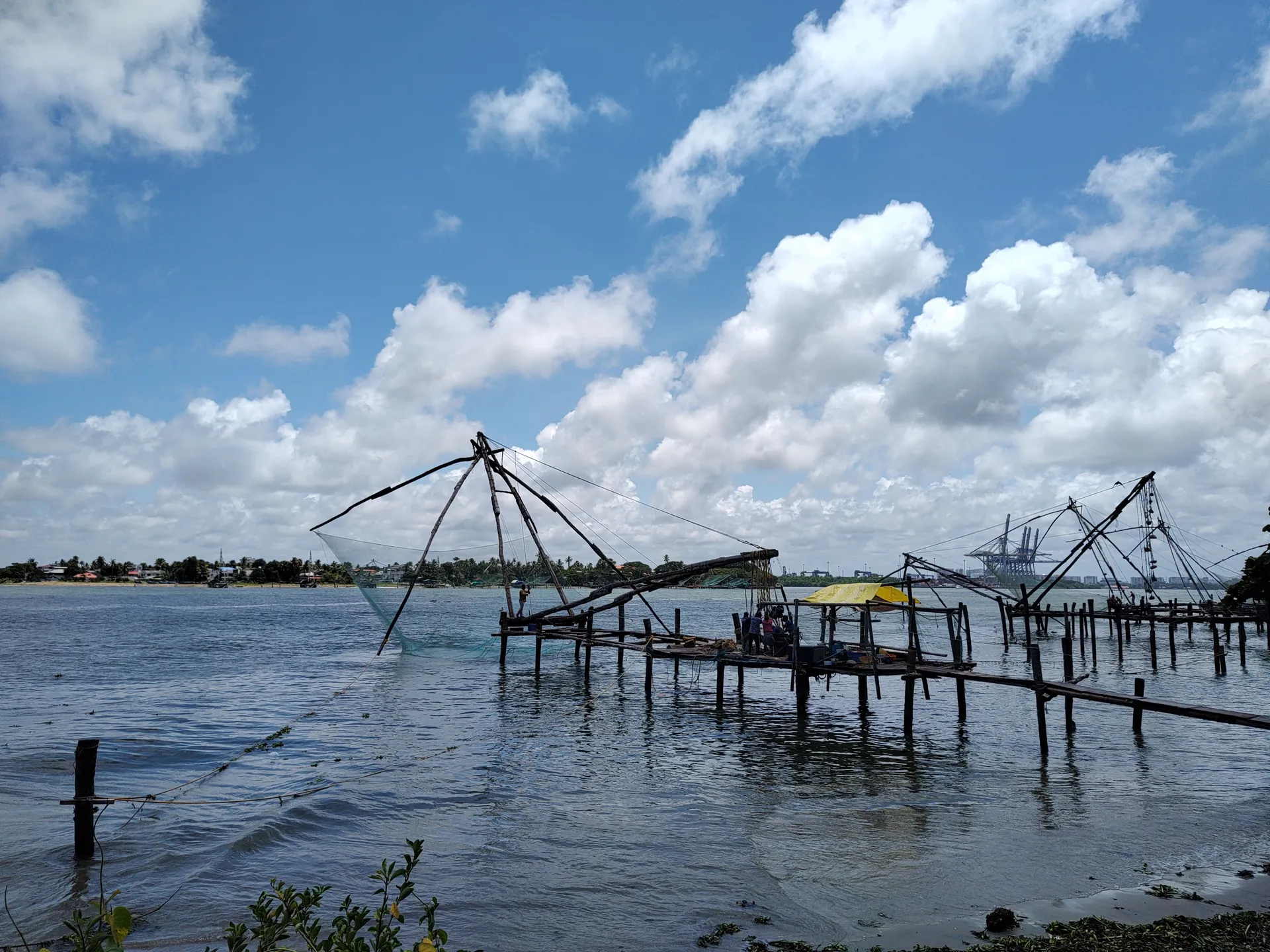 Traditional Chinese fishing nets silhouetted against a clear blue sky in Kerala.