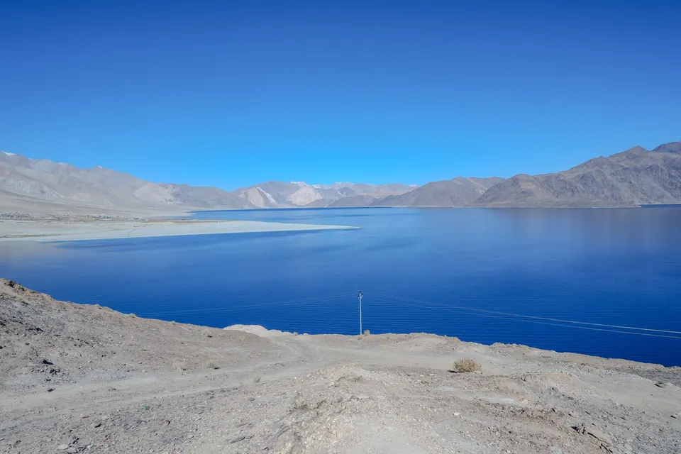 Captivating view of Pangong Lake with clear blue skies and mountain backdrop.