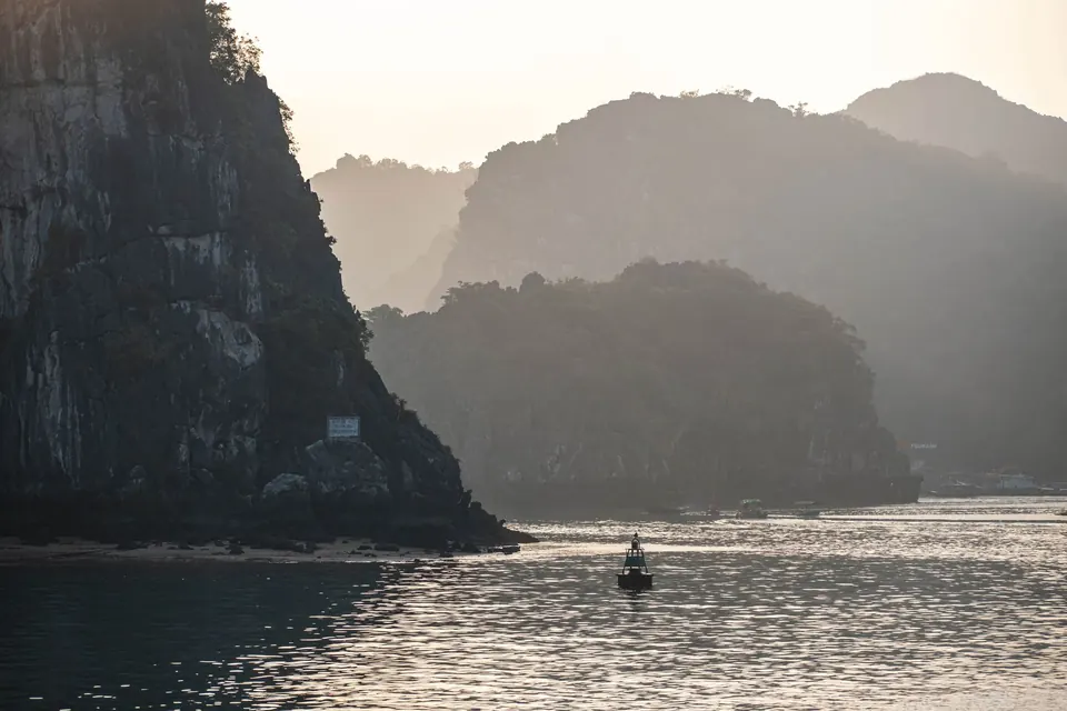 Peaceful view of Ha Long Bay with limestone cliffs in the evening light.