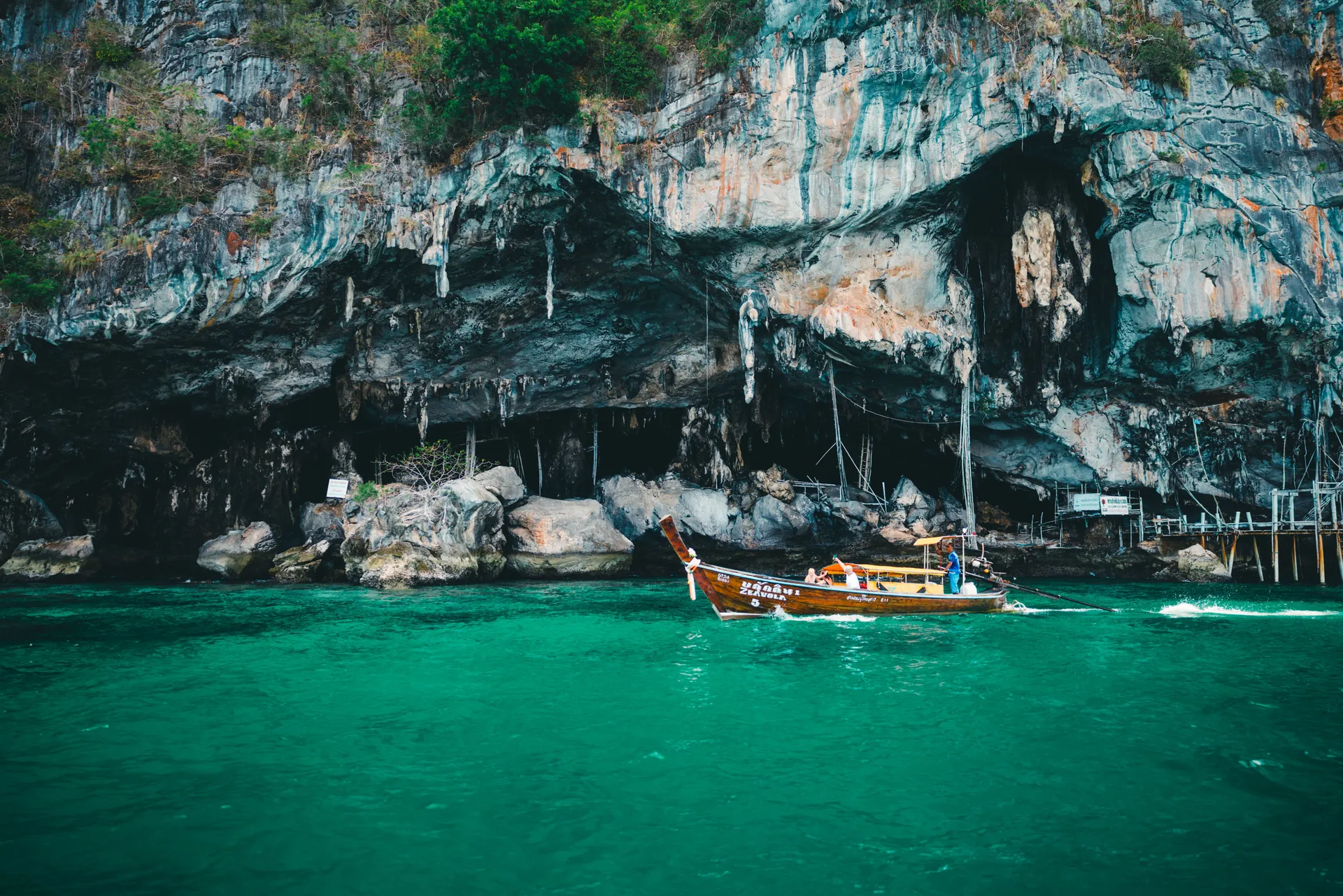 Explore the stunning limestone cliffs of Phuket with a traditional longtail boat on emerald waters.