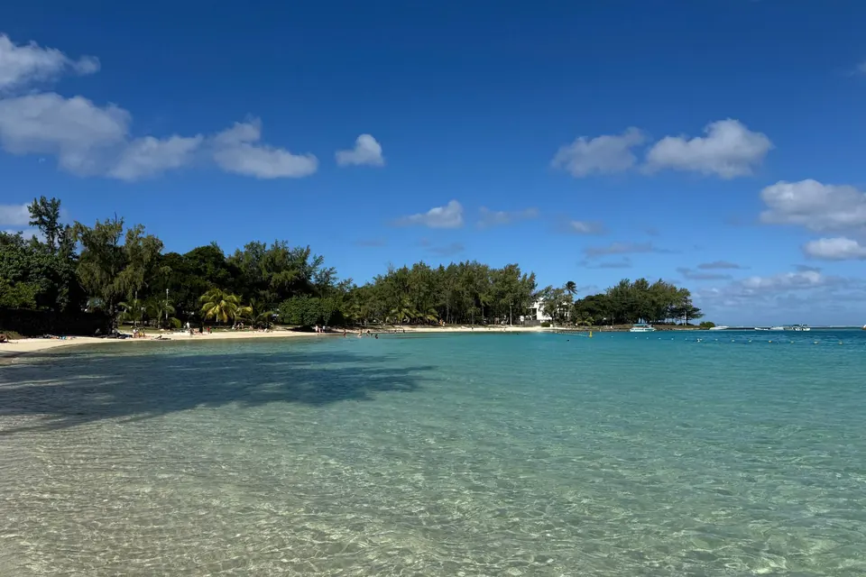 Pristine beach in Blue Bay, Mauritius with clear blue water and a sunny sky.
