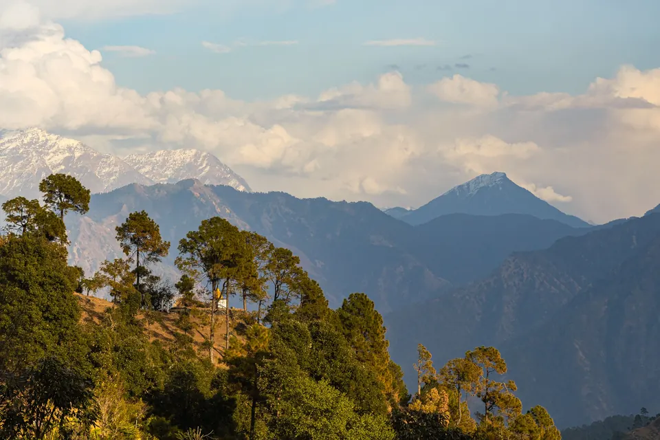 Scenic landscape of the Himalayas from Uttarakhand, featuring lush greenery and distant snow-capped peaks.