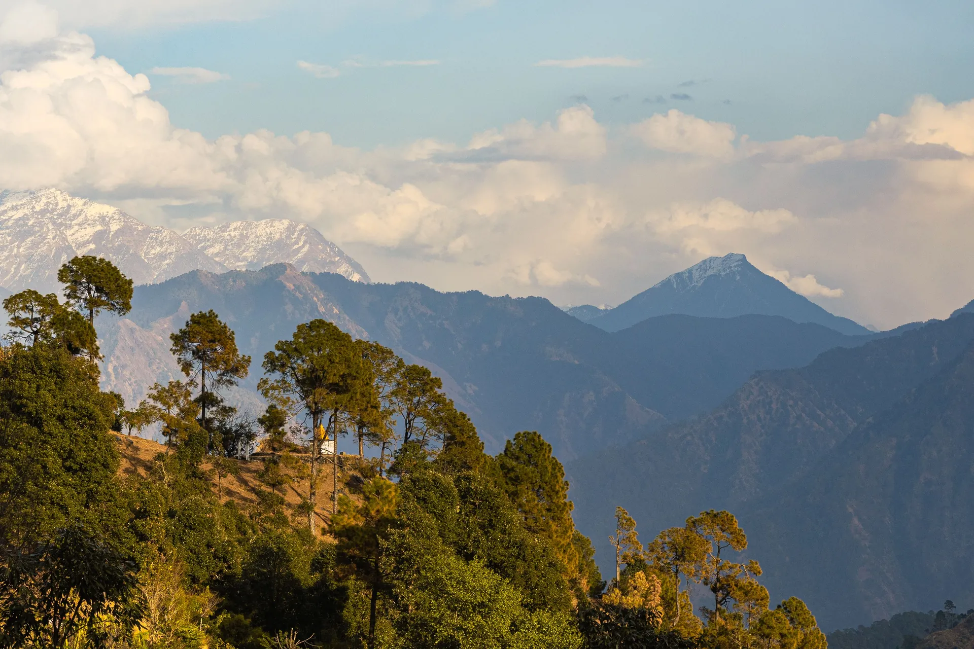 Scenic landscape of the Himalayas from Uttarakhand, featuring lush greenery and distant snow-capped peaks.
