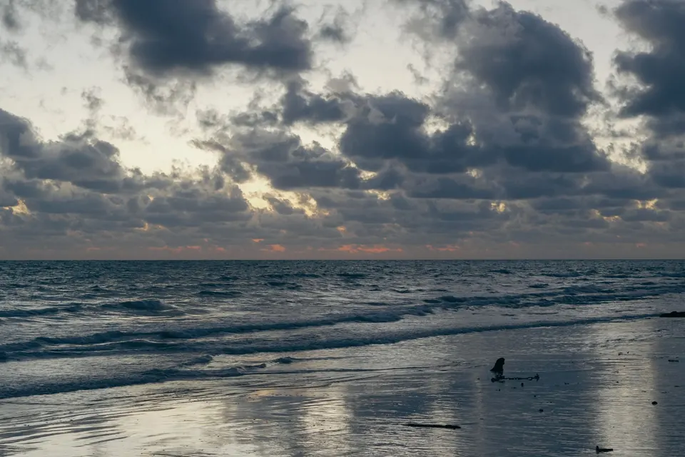 Calm waves and dramatic clouds create a picturesque sunset at Andaman Islands.