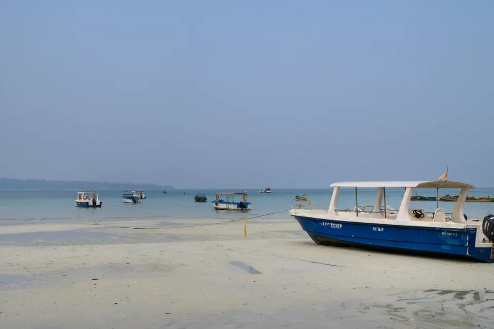A blue and white boat sitting on top of a sandy beach.